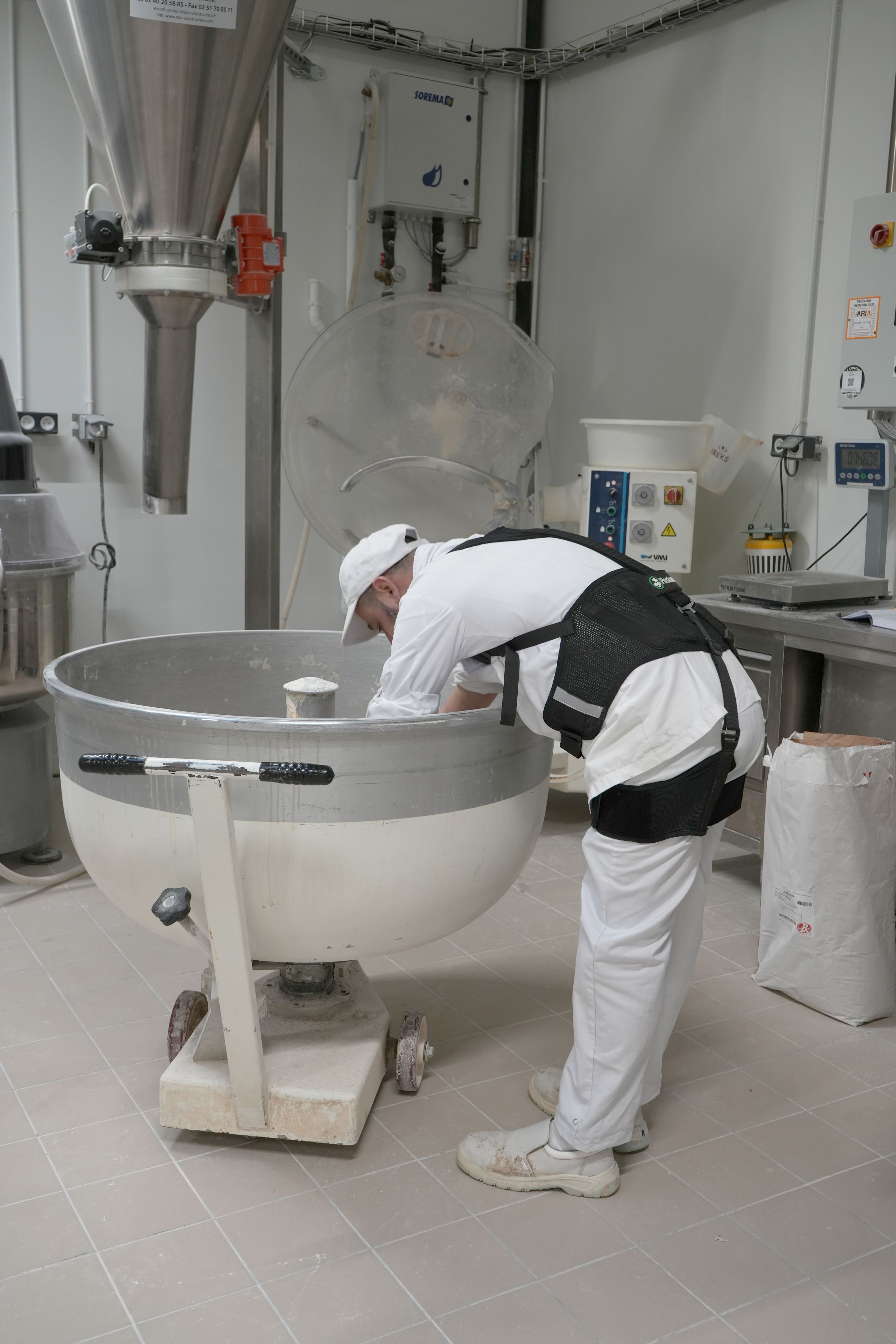 Boulanger équipé d’un exosquelette devant un pétrin