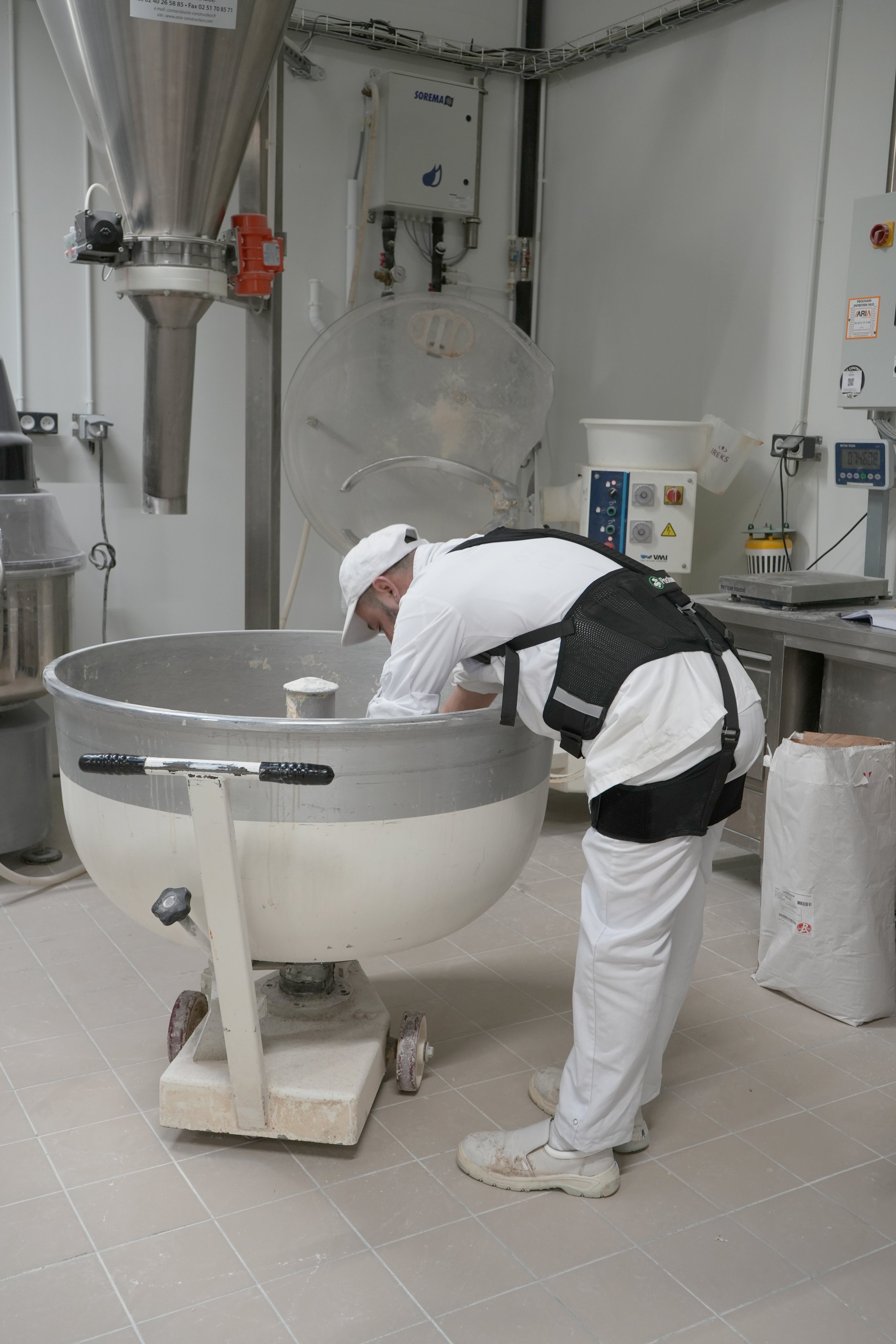Boulanger équipé d’un exosquelette devant un pétrin